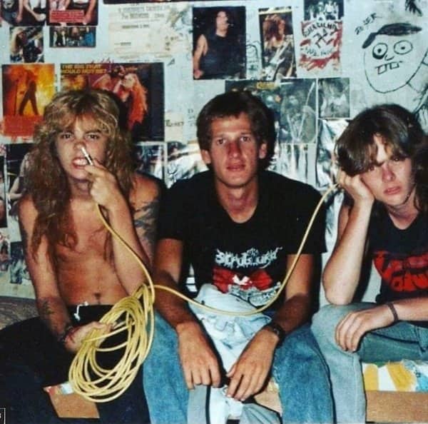 Young rock fans in retro bedroom surrounded by heavy metal posters holding microphone cord.