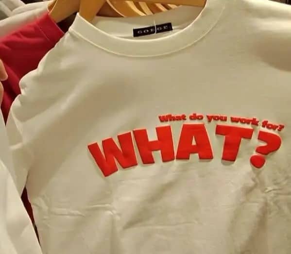 White sweatshirt featuring red raised lettering asking what do you work for WHAT in apparel.