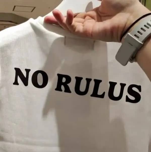 White shirt with bold back graphic text misspelled as no rulus in black print