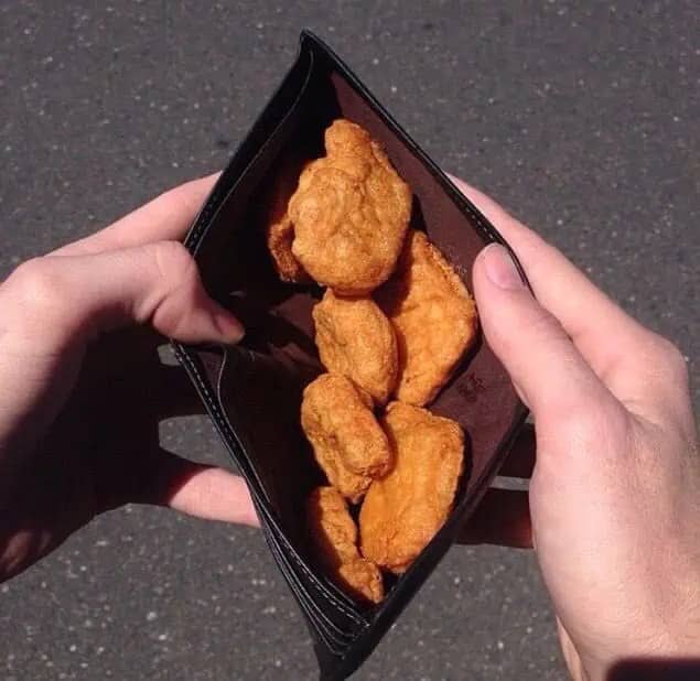 Open leather wallet stuffed with chicken nuggets, held in a first person shot.