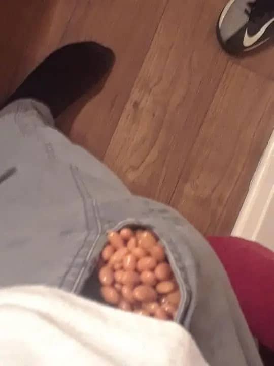 Baked beans packed into a torn jeans pocket in a first person pov memes shot.