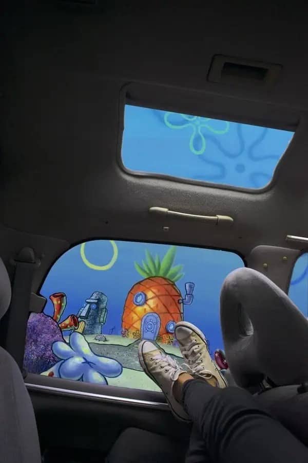 Feet up in a car with SpongeBob's pineapple house and Bikini Bottom outside the window.