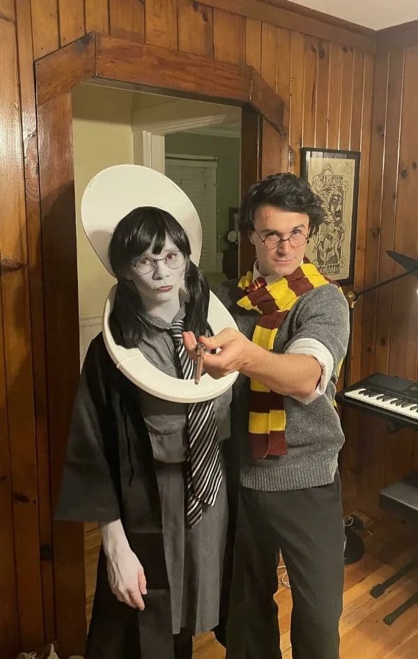 Couple in Halloween costumes as Harry Potter and Moaning Myrtle wearing a toilet seat.