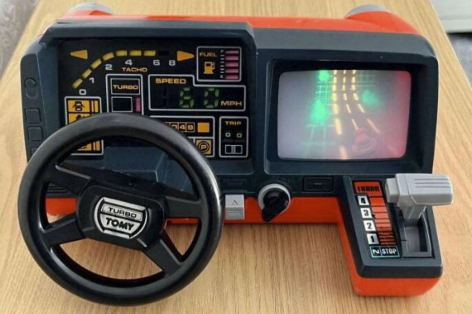 A nostalgic retro tech digital gallery showcasing classic analog gadgetry and early computing, featuring a bright yellow Casio cassette guitar, a clear 90s see-through landline phone revealing internal electronics, and a guy blowing into a dusty NES game cartridge.