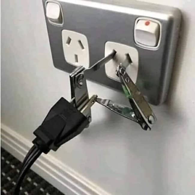 Nail clippers jammed into a wall socket beside a power plug to complete a connection