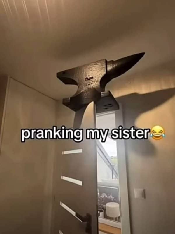 Heavy metal anvil balanced delicately above a cracked door in a house.