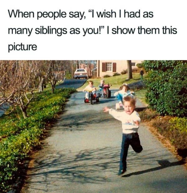 Young boy running away in panic from siblings riding tricycles down a driveway.
