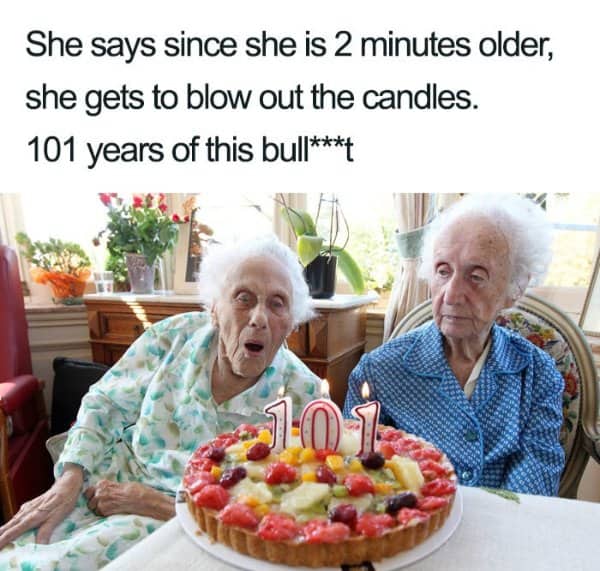 Elderly twin sisters celebrating 101st birthday while one blows out the candles.