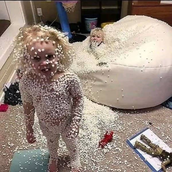 Two young children completely covered in tiny white beanbag foam beads.