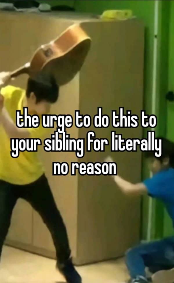 Person swinging an acoustic guitar overhead toward another person sitting down.