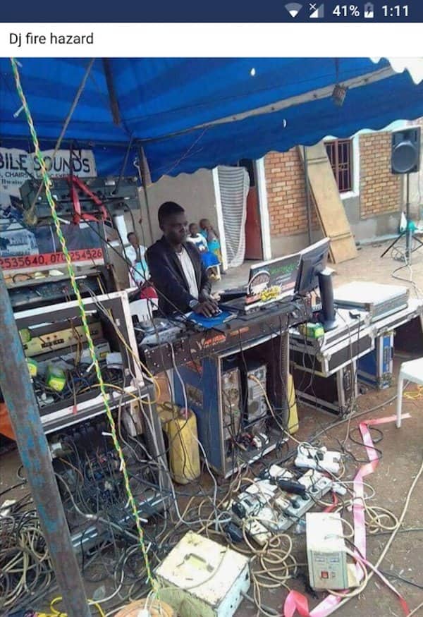 Outdoor DJ booth surrounded by a massive tangle of cables and power strips.