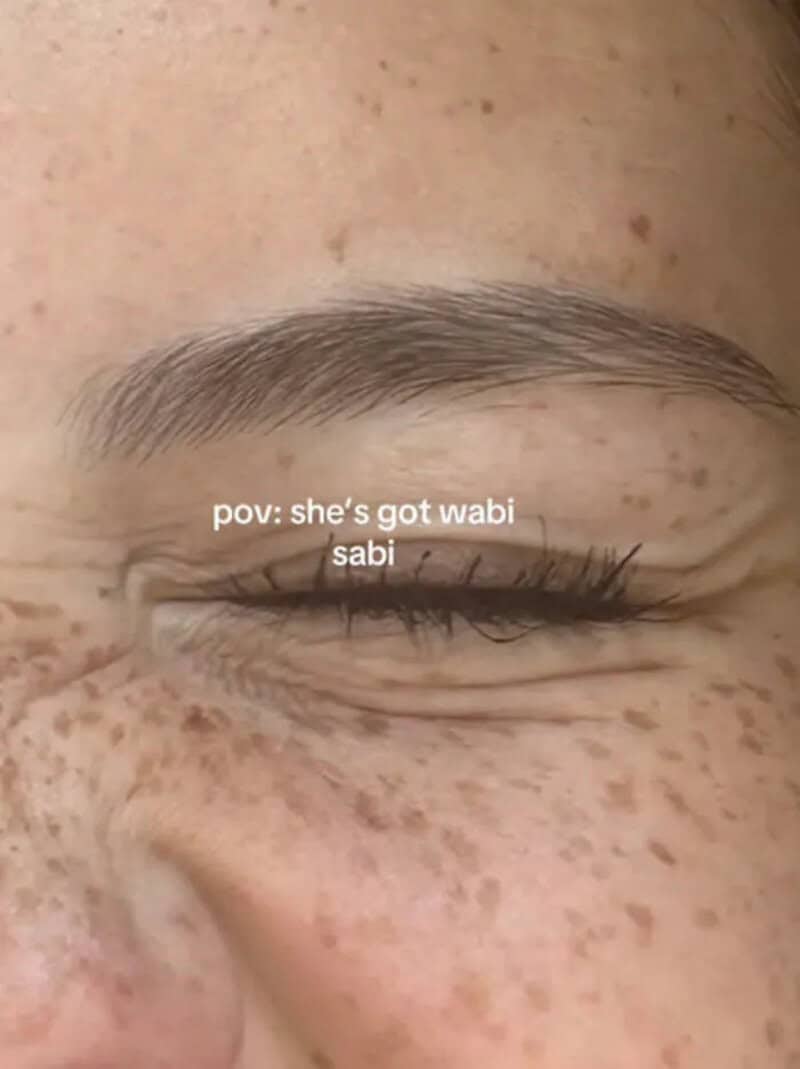 Close up of freckles around a closed eye celebrating natural human wabi sabi features.